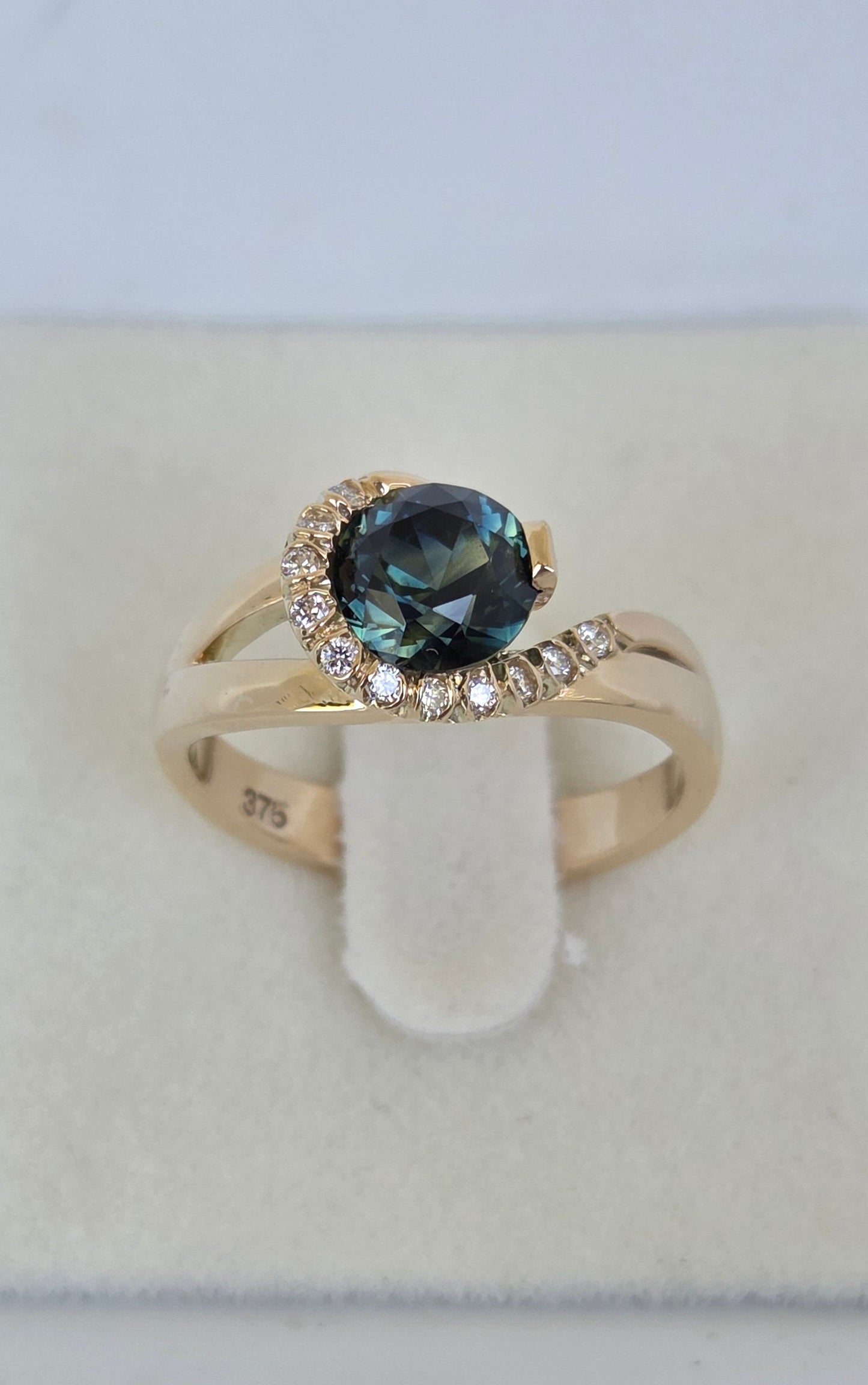 Blue Parti Sapphire custom made ring with diamond set spiral curl surround     Design Ref: #01557